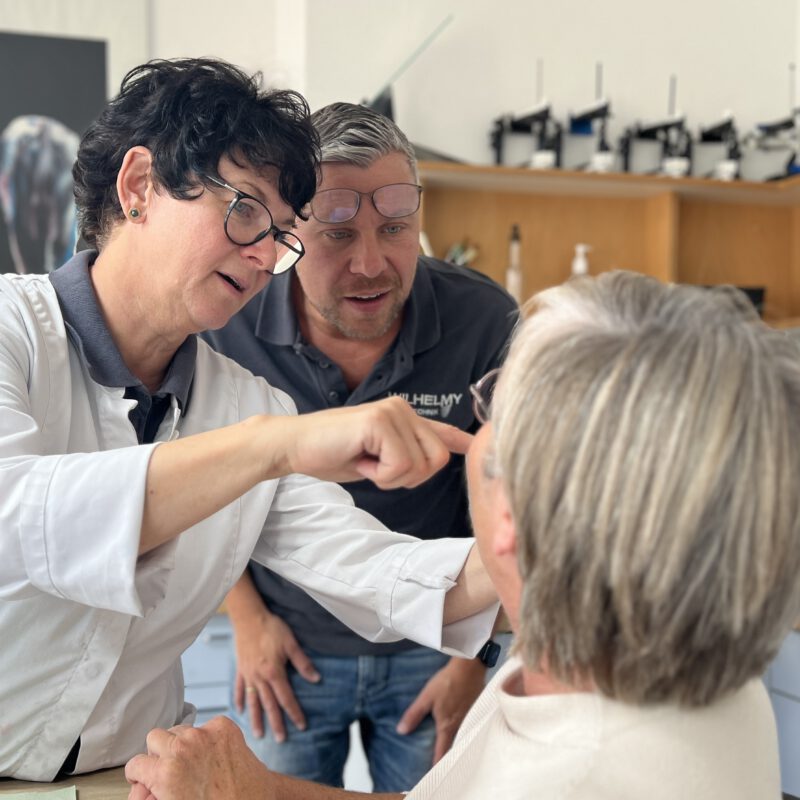 Zwei Techniker begutachten die Zahnfarbe einer Patientin